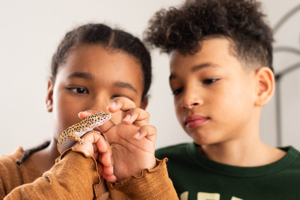 Two youth group members care for a lizard