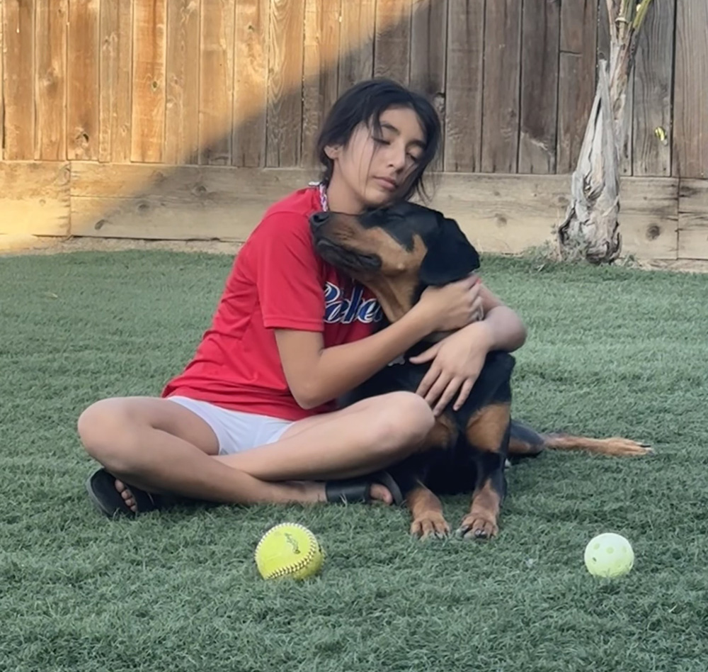 Ivy Ruiz's daughter Xani hugs her dog Renzo