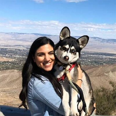 Photo of Sheila in a blue shirt holding her Husky mix, Ziba